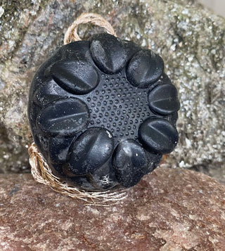 charcoal loofah foot soap leaning against a rock